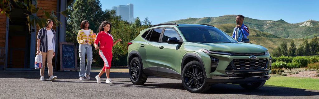 Green Chevrolet SUV parked outdoors with people walking nearby in a scenic landscape.
