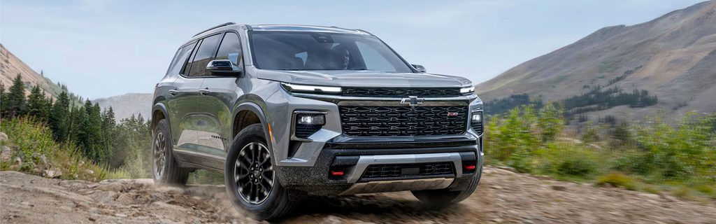 Chevrolet SUV driving on a rugged mountain trail with a scenic outdoor landscape in the background.