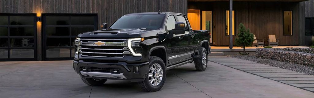 Black Chevrolet pickup truck parked outside a modern home with a contemporary design.