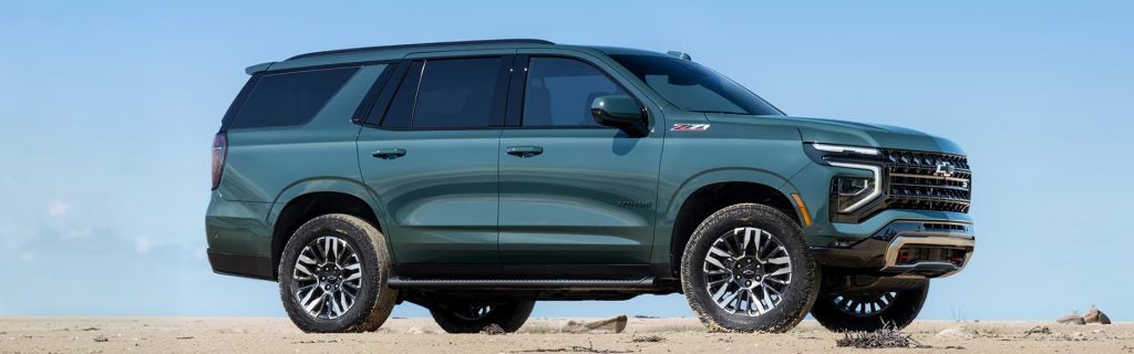 Green Chevrolet Tahoe Z71 SUV parked on sandy terrain.