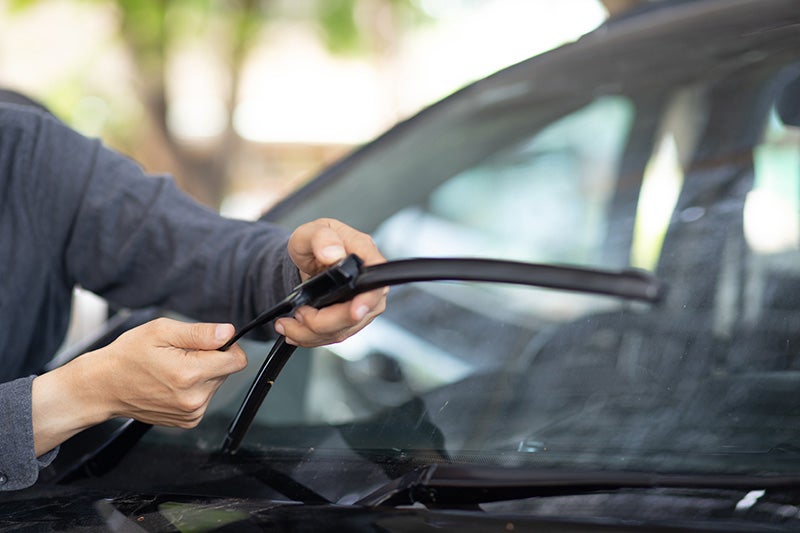 A Mechanic installing a new windshield wiper blade on a car.