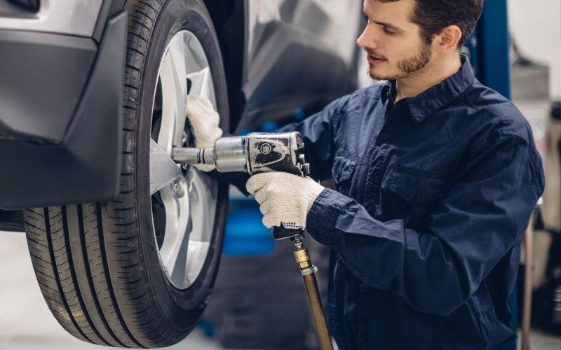 Mechanic performing a tire rotation on a vehicle.